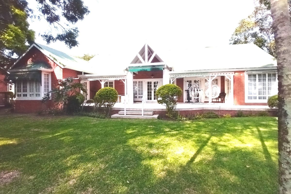 A charming red brick house featuring a spacious covered patio, classic french doors, and a well-maintained garden setting.