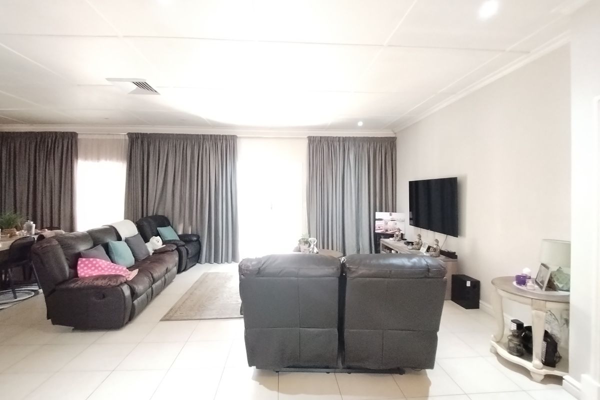 Spacious living room featuring neutral tiled flooring, recessed downlighting, and ceiling coving, providing a bright and comfortable area for relaxation.