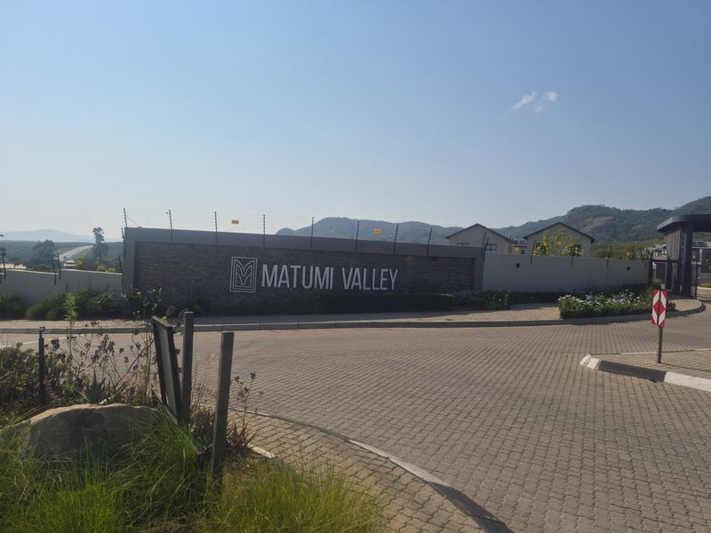 Entrance view of Matumi Valley estate featuring a stone-clad perimeter wall, electric fencing, and paved driveway access.