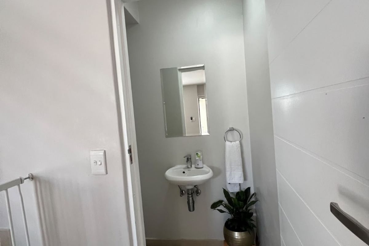 A compact guest bathroom featuring a wall-mounted basin, tiled flooring, and a minimalist design.