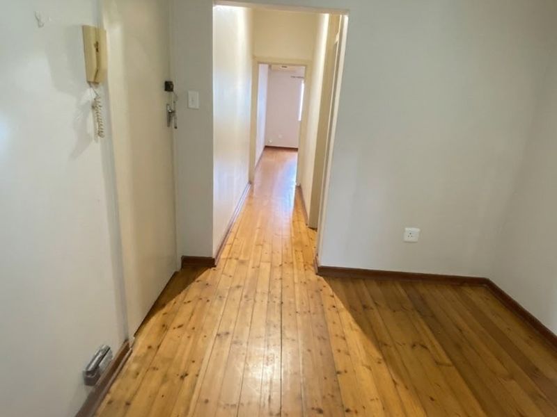 A vacant hallway featuring polished timber flooring and an integrated intercom system, providing access to adjacent living areas.