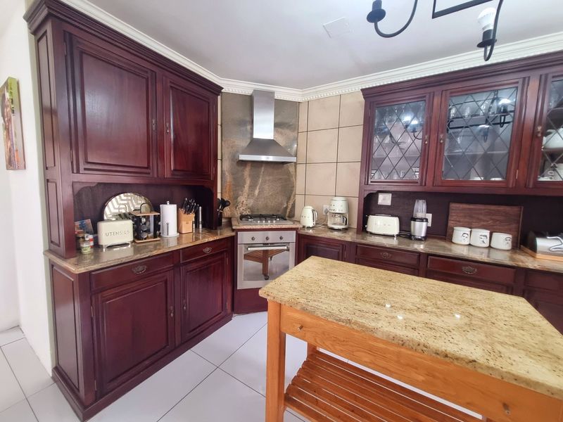 Traditional kitchen featuring dark wood cabinetry, granite countertops, stainless steel appliances, and tiled flooring with decorative crown molding.