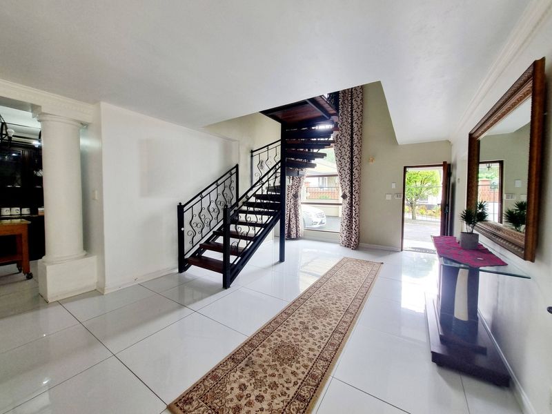 Spacious entrance hall featuring a striking spiral staircase with wrought iron detailing, polished porcelain floor tiles, and direct access to the front exterior.