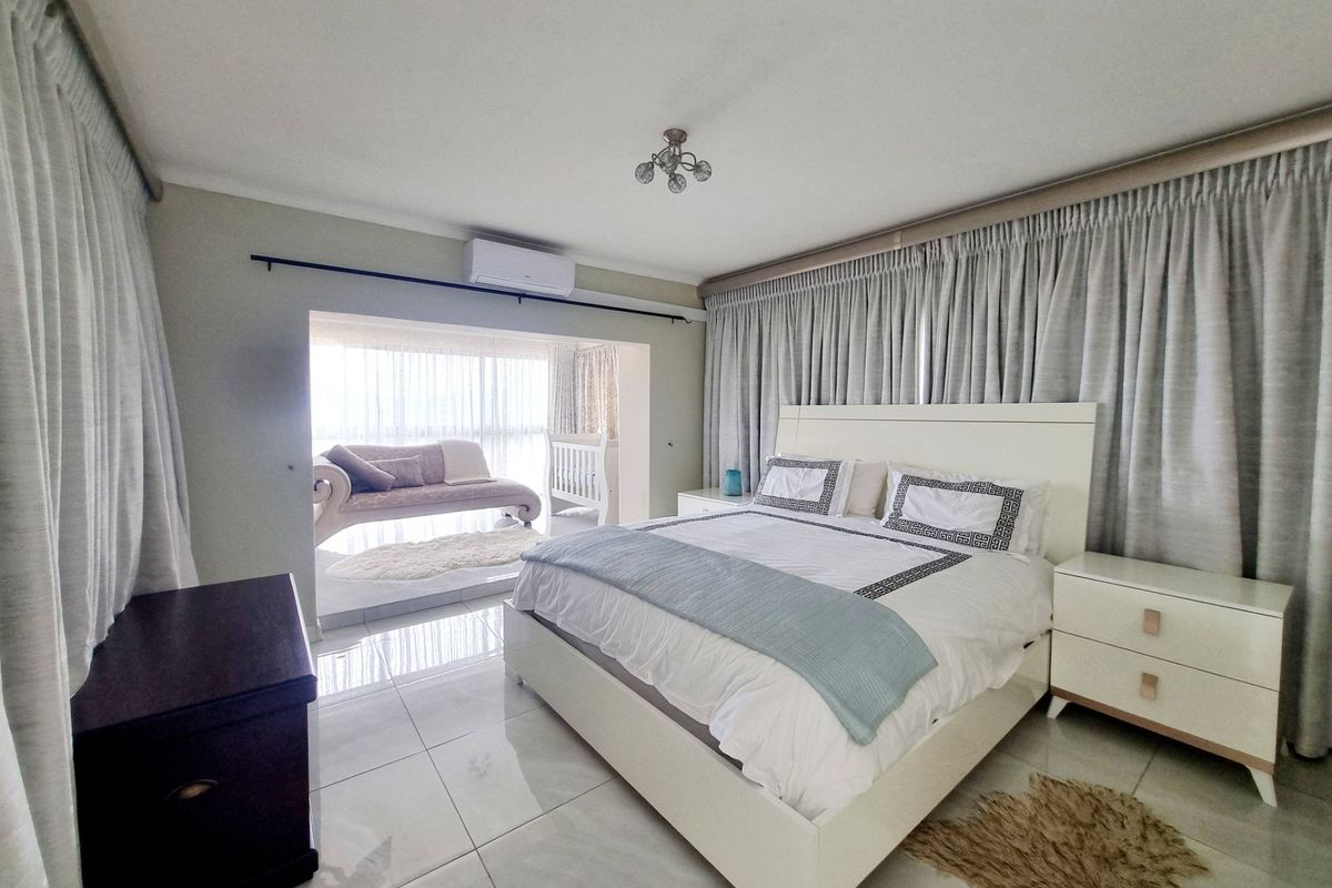 Spacious bedroom featuring tiled flooring, a split-system air conditioner, and a bright, recessed alcove area suitable for a seating nook or nursery.