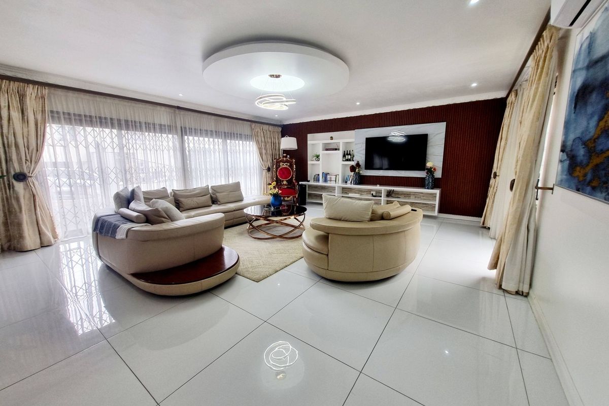 Spacious living room featuring polished porcelain floor tiles, a modern recessed ceiling design, and a custom built-in media wall unit.