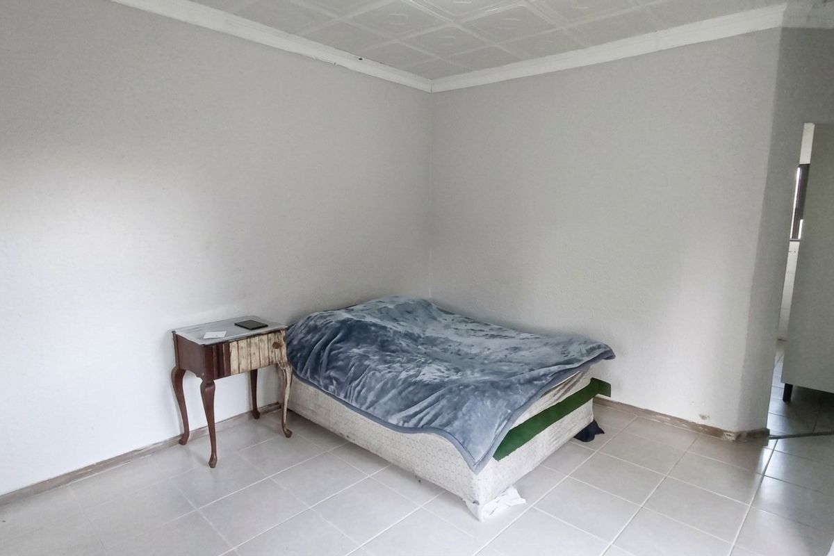 A simple bedroom featuring tiled flooring and a coved ceiling, offering a blank canvas for potential interior updates.