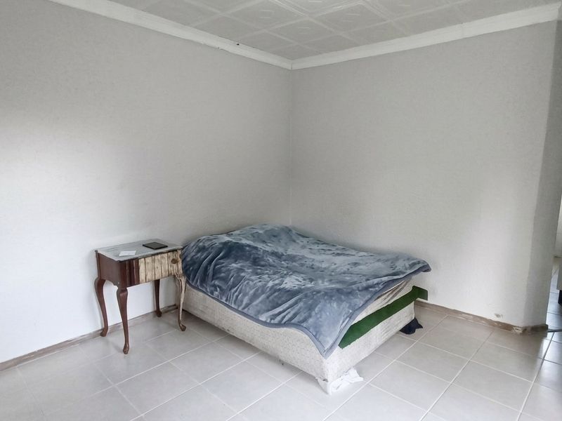 A simple bedroom featuring tiled flooring and a coved ceiling, offering a blank canvas for potential interior updates.