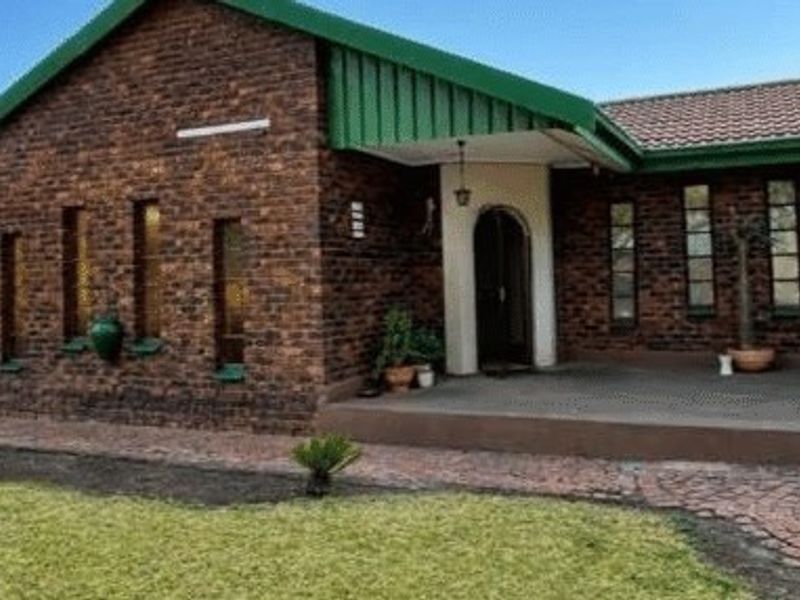 A charming face brick house featuring a covered front porch, arched entrance, and a well-maintained paved driveway and front lawn.