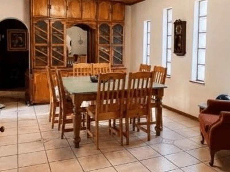 A traditional dining room featuring built-in wooden cabinetry, tiled flooring, and an arched doorway leading to adjacent living spaces.