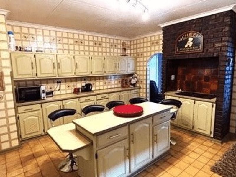 A spacious kitchen featuring a central island, extensive built-in cabinetry, and a distinctive brick feature wall with a built-in cooking area.
