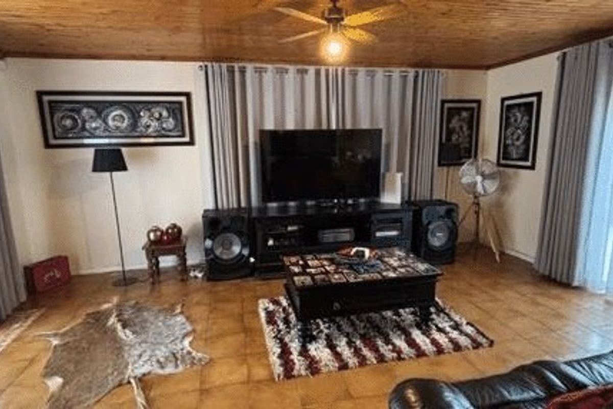 Spacious living room featuring a warm timber-paneled ceiling, ceiling fan, and durable tiled flooring with dual access to outdoor areas.