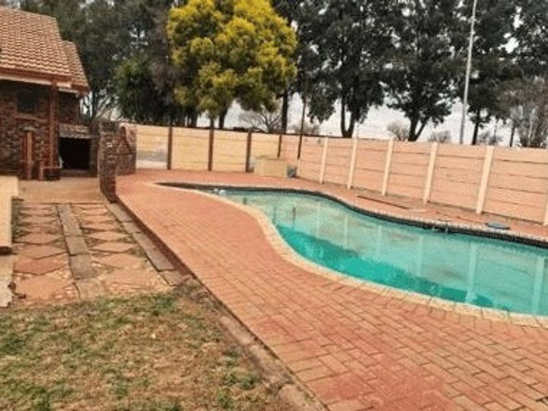 Outdoor pool area featuring a swimming pool, brick paving, and a surrounding precast concrete boundary wall.