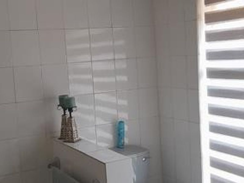 A functional bathroom featuring white wall tiles and a fitted roller blind for privacy.