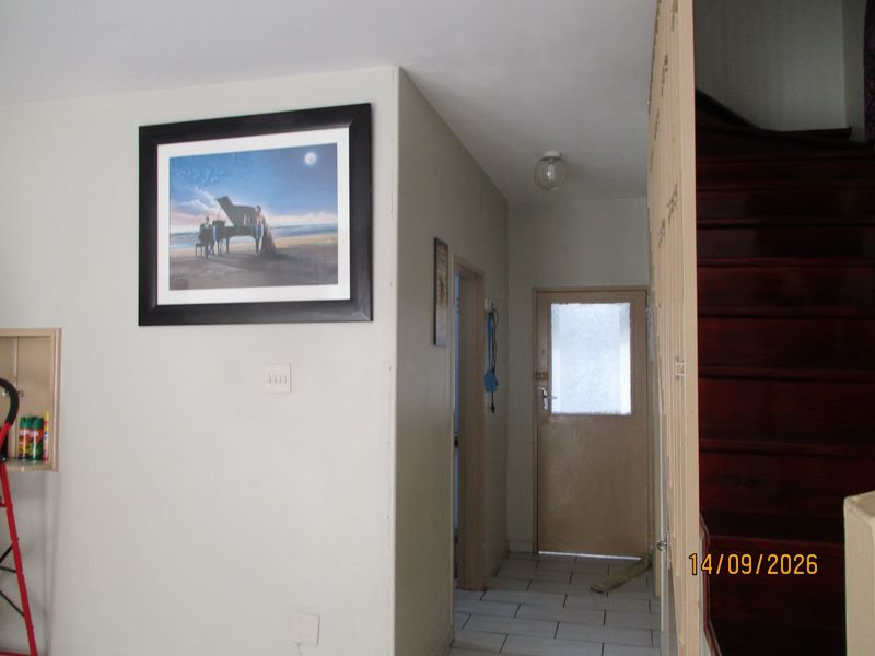 Entrance area featuring a wooden staircase, tiled flooring, and access to an external door.