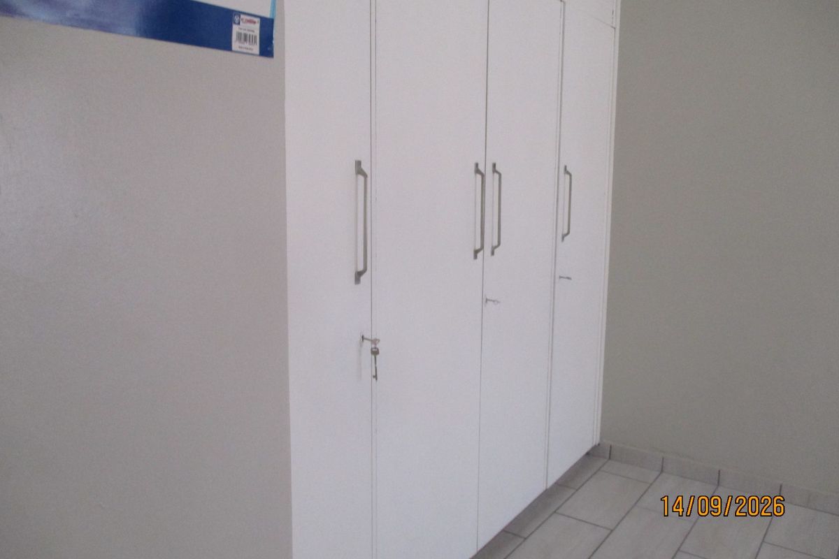 A bedroom interior featuring white built-in cupboards and tiled flooring.