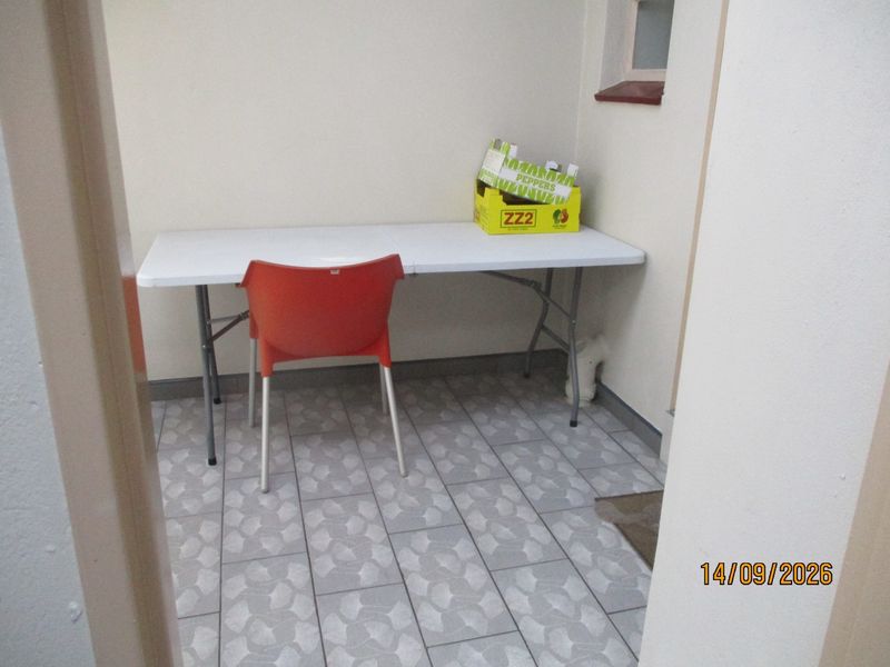 A small, functional utility space featuring tiled flooring and a window, suitable for storage or a compact workspace.