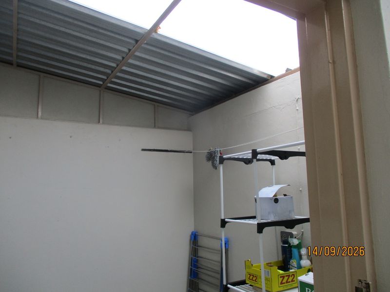 A functional laundry or utility area featuring a corrugated metal roof and a fixed wall-mounted clothesline.
