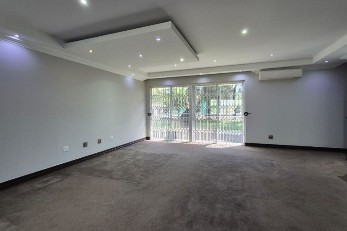 Spacious living room featuring recessed ceiling lighting, air conditioning, and sliding glass doors with security gates leading to the exterior.