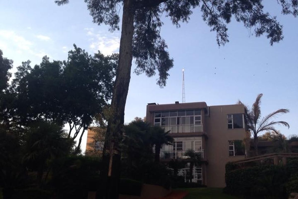 A view of the rear elevation of a multi-story house featuring balconies and a well-maintained garden area.