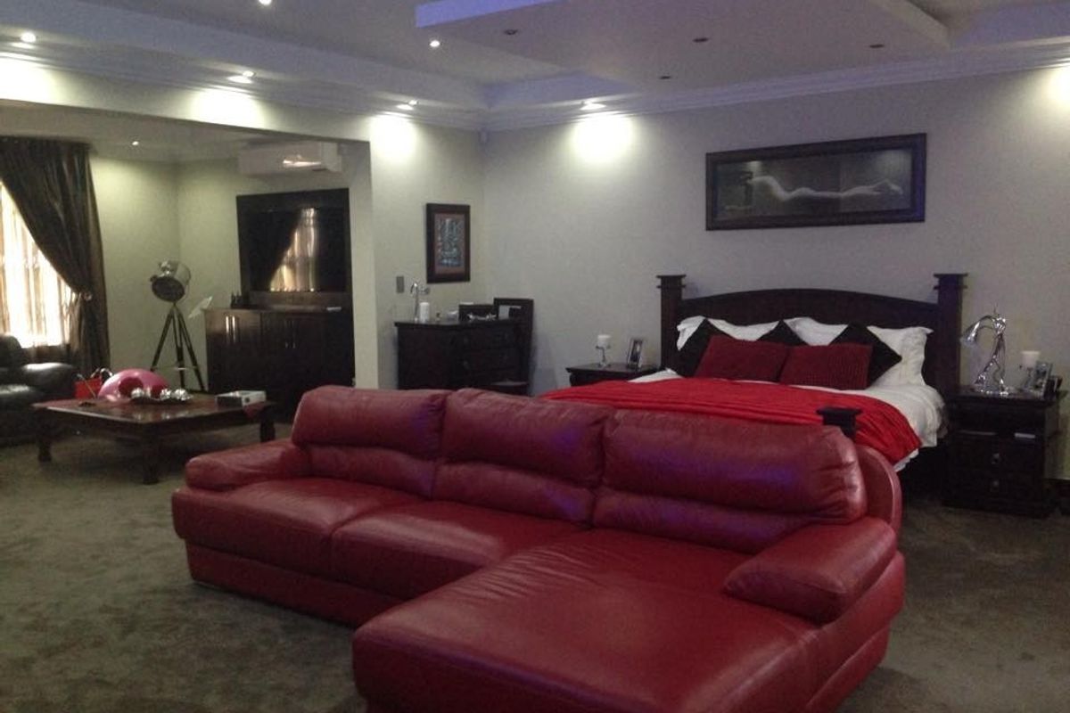 Spacious bedroom featuring a recessed ceiling with integrated downlighting and a wall-mounted air conditioning unit.