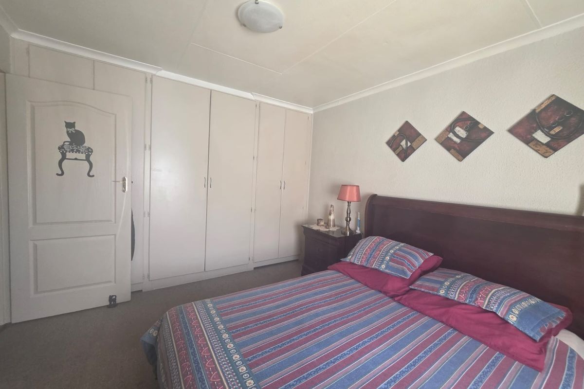 A functional bedroom featuring built-in cupboards, neutral wall finishes, and carpeted flooring, offering a comfortable and practical living space.