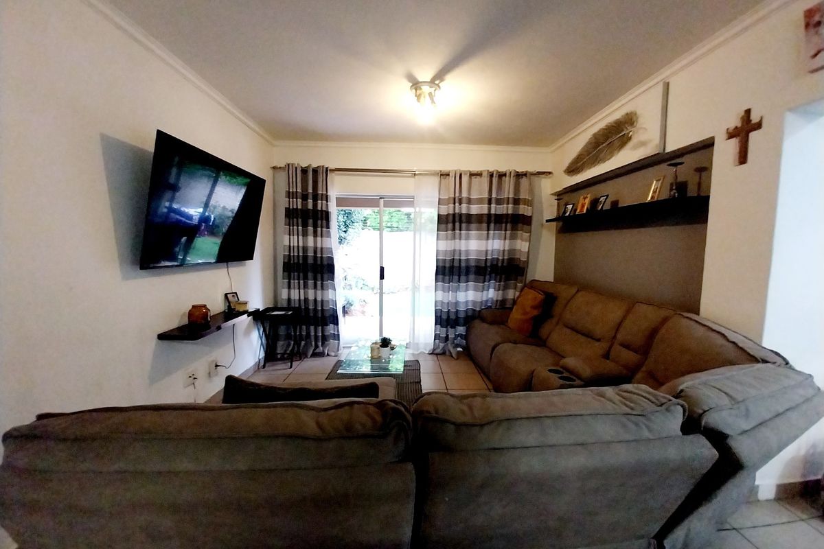 A comfortable living room featuring tiled flooring, a built-in wall shelf, and a sliding glass door providing access to the outdoor area.