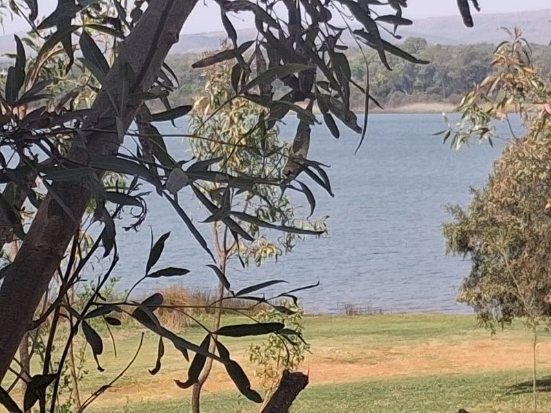 A scenic view of the lake and surrounding landscape, framed by trees on the vacant residential property.