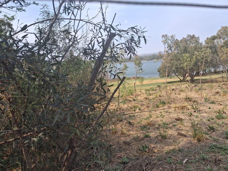 A scenic view of the landscape and water body from the vacant residential property, featuring natural vegetation and perimeter wire fencing.