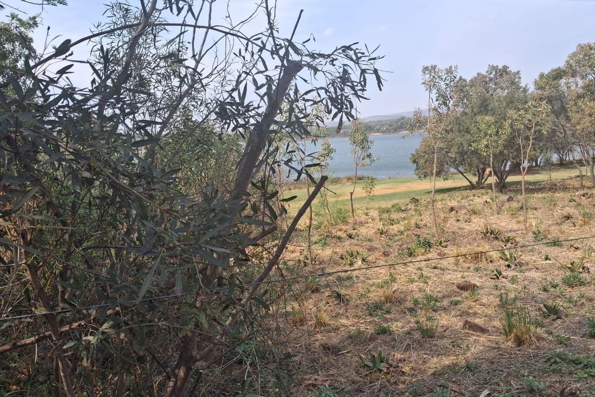 A scenic view of the landscape and water body from the vacant residential property, featuring natural vegetation and perimeter wire fencing.