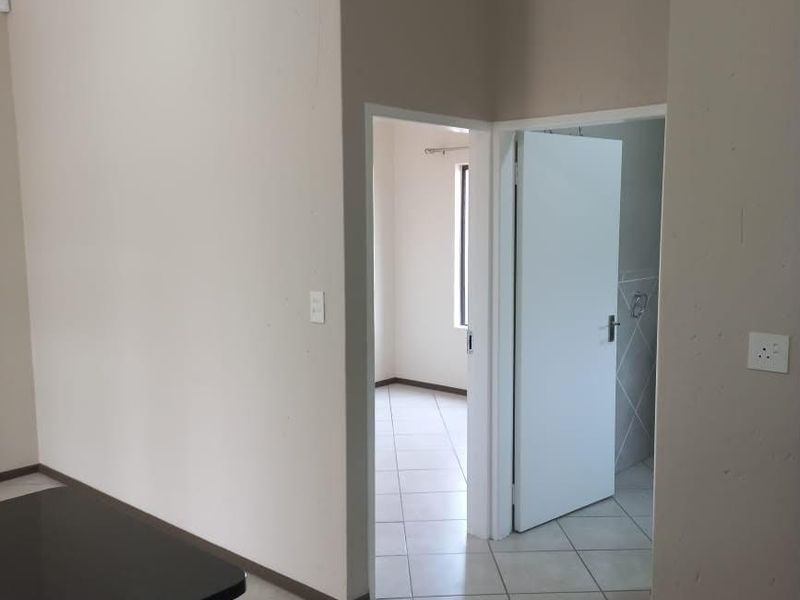 A neutral-toned hallway featuring tiled flooring and coved cornicing, providing access to adjacent rooms within the apartment.