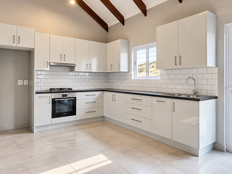 Modern kitchen featuring white cabinetry, subway tile backsplash, built-in oven and hob, and exposed timber ceiling beams with direct access to an outdoor patio.