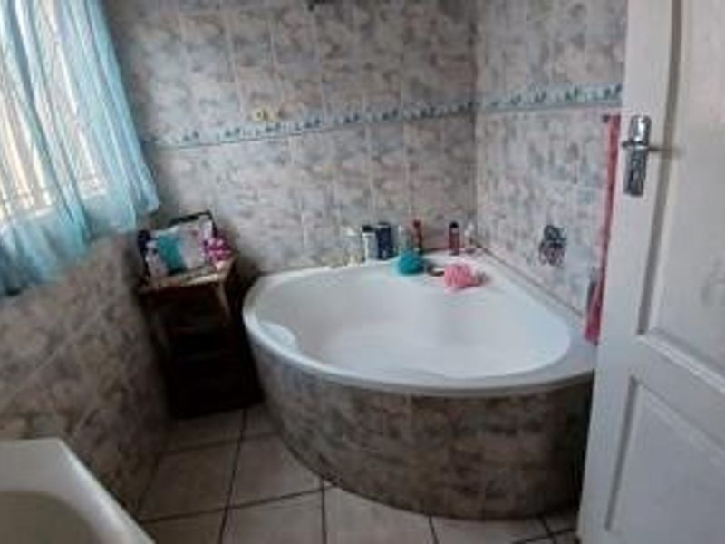 A functional bathroom featuring a corner bathtub, tiled wall finishes, and floor tiling, providing a standard layout for the home.