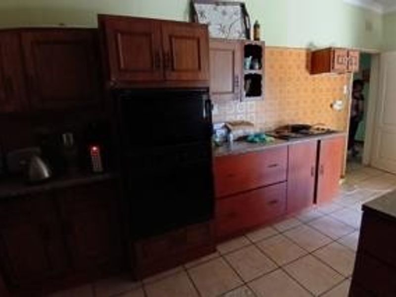 A dated kitchen featuring traditional wooden cabinetry, tiled backsplash, and tiled flooring, offering significant potential for a modern renovation.