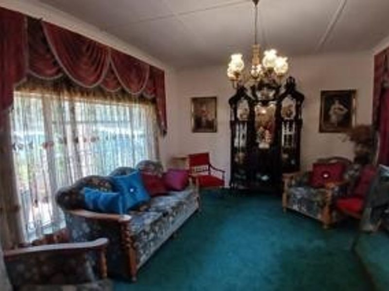 A traditional living room featuring a central chandelier and a built-in display cabinet, offering a classic layout with large windows.