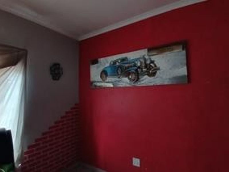 A bedroom interior featuring a red accent wall with decorative brick-effect detailing and standard electrical fixtures.