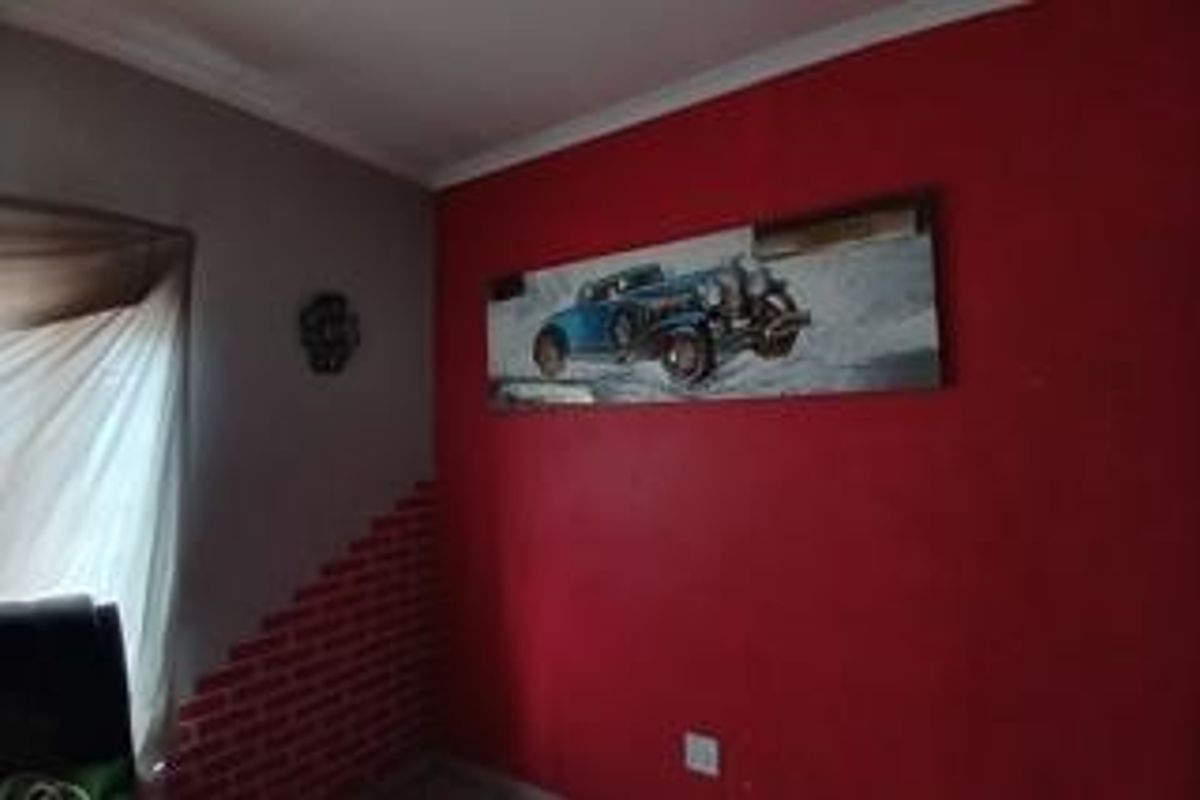 A bedroom interior featuring a red accent wall with decorative brick-effect detailing and standard electrical fixtures.