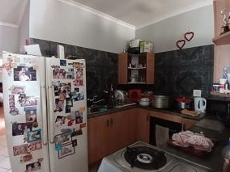 A functional kitchen featuring built-in cabinetry, a hob, an oven, and a tiled backsplash, offering a practical layout for daily meal preparation.