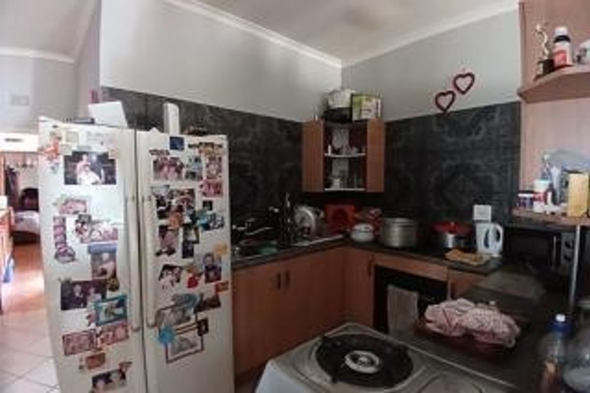 A functional kitchen featuring built-in cabinetry, a hob, an oven, and a tiled backsplash, offering a practical layout for daily meal preparation.