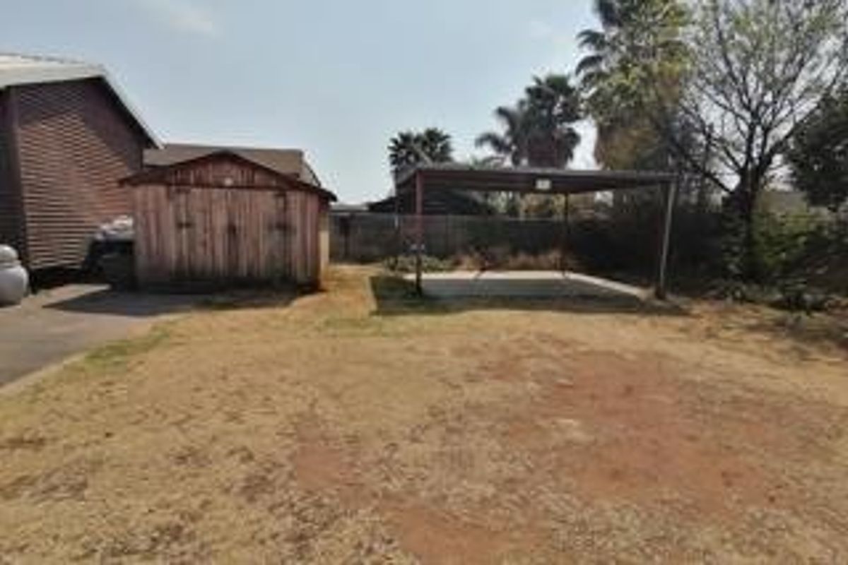 Rear yard featuring a detached timber shed, a metal carport structure, and a concrete parking area.