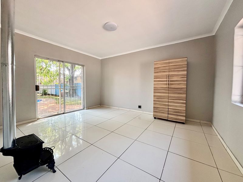 A bright, tiled living area featuring a freestanding fireplace and a sliding glass door that opens to the garden.