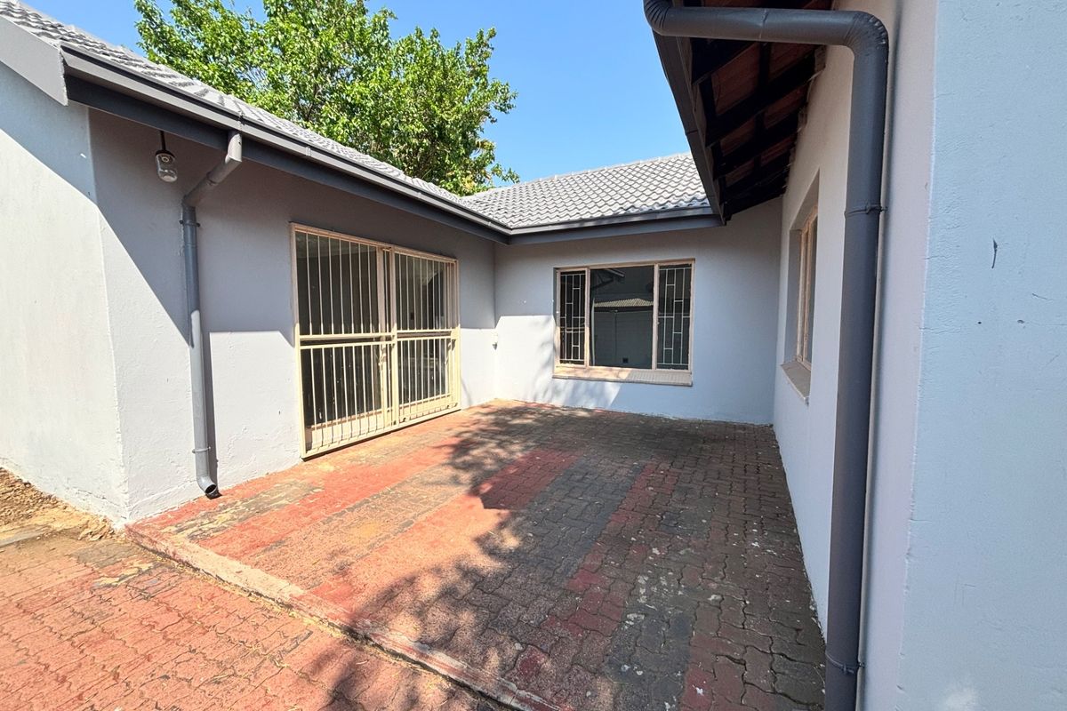 A paved rear courtyard area featuring security gates and bars, providing a functional outdoor space with potential for landscaping or patio furniture.