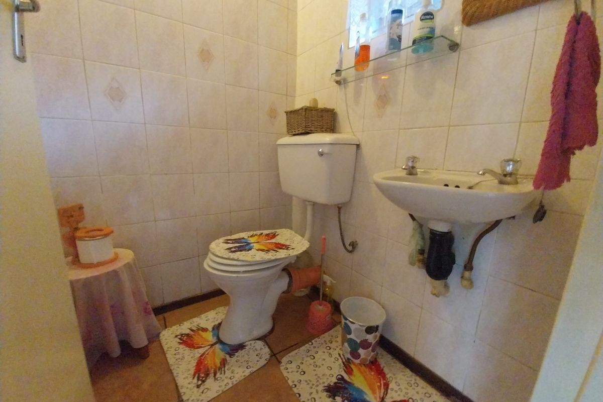 A compact guest bathroom featuring a wall-mounted basin, toilet, and full-height ceramic wall tiling.