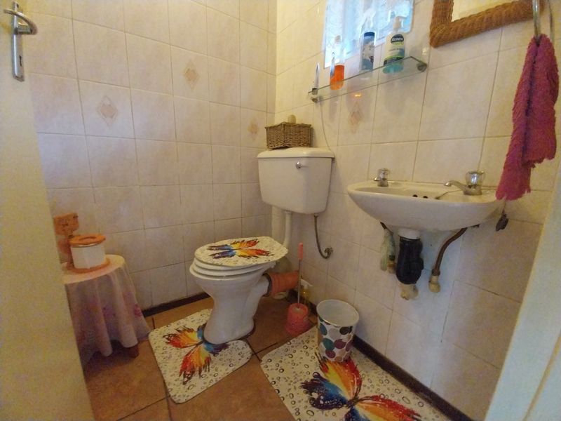 A compact guest bathroom featuring a wall-mounted basin, toilet, and full-height ceramic wall tiling.