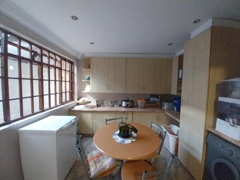 A functional kitchen featuring built-in cabinetry, laminate countertops, and timber-framed windows, offering a practical layout with potential for modern updates.
