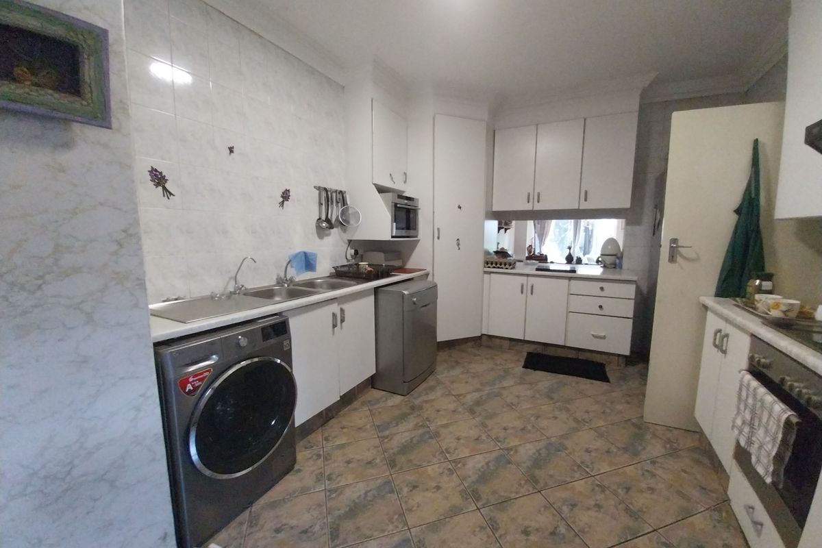 Functional kitchen featuring white cabinetry, tiled backsplash, double sink, and built-in oven with tiled flooring throughout.