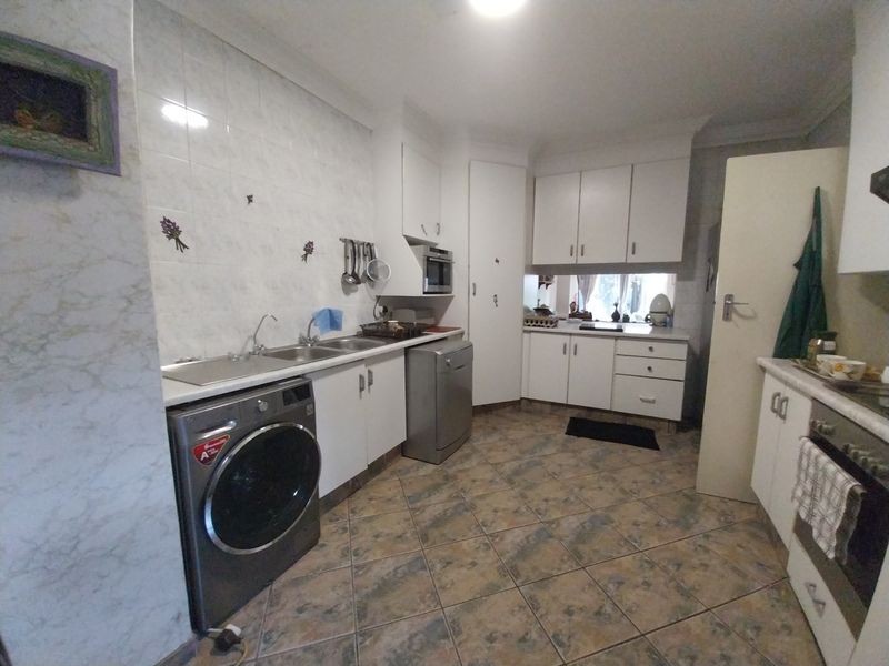 Functional kitchen featuring white cabinetry, tiled backsplash, double sink, and built-in oven with tiled flooring throughout.