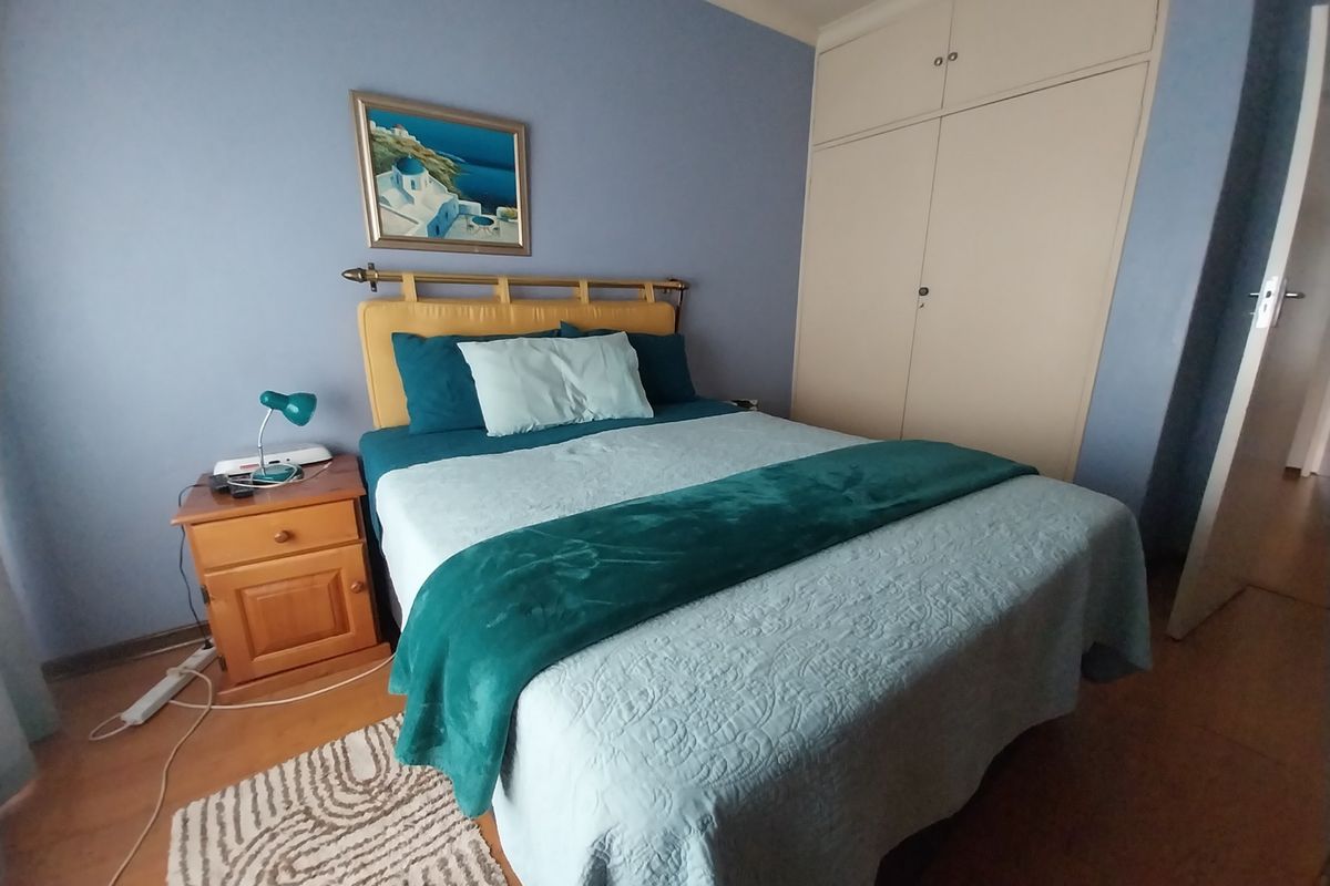 A bedroom featuring built-in cupboards and laminate flooring, providing a functional and comfortable living space.