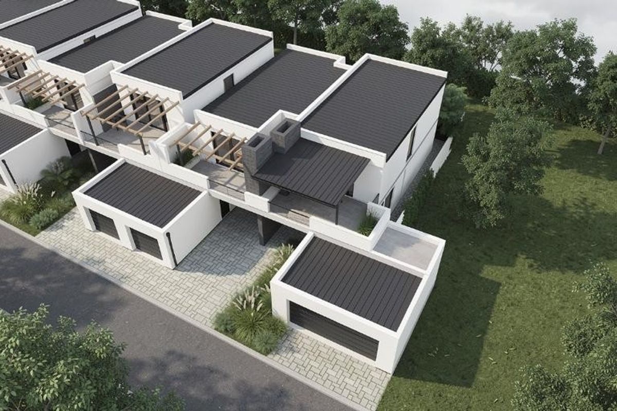 Aerial view of a modern townhouse development featuring clean architectural lines, flat roofs, integrated garages, and paved driveways set within a landscaped environment.