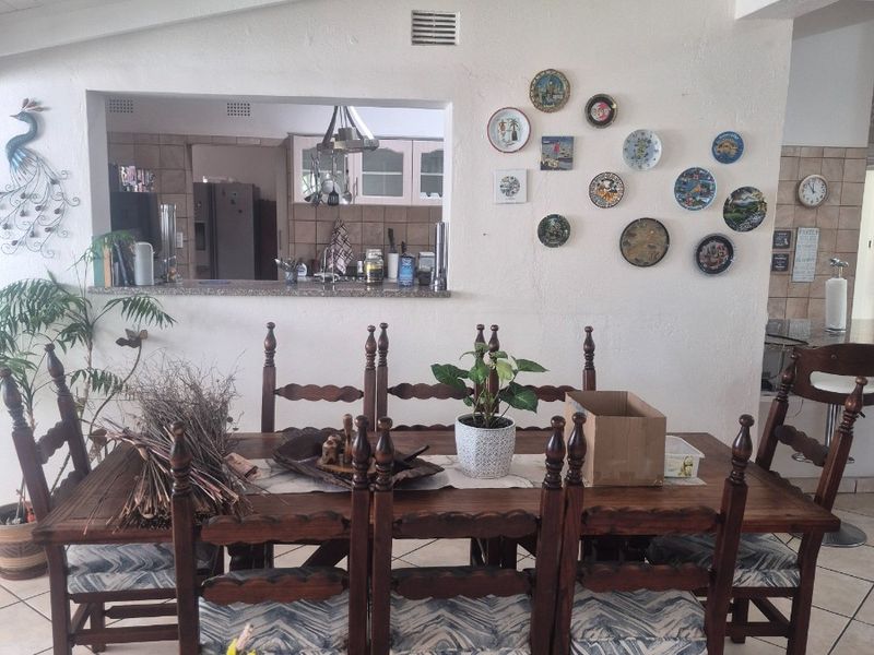 Open plan dining area featuring a vaulted ceiling, tiled floors, and a convenient pass-through window connecting to the kitchen.