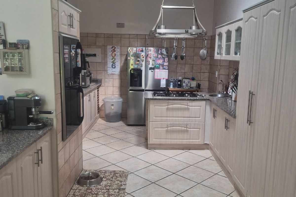 A functional kitchen featuring light-toned cabinetry, granite countertops, a gas hob, and a vaulted ceiling, offering a practical layout for daily cooking.
